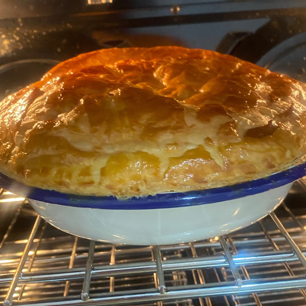 Baked steak and guinness pie in an oven with a blue rimmed dish